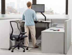 A person works at an ergonomic sit/stand desk