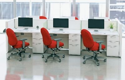 Three red office chairs sit in front of white workstations