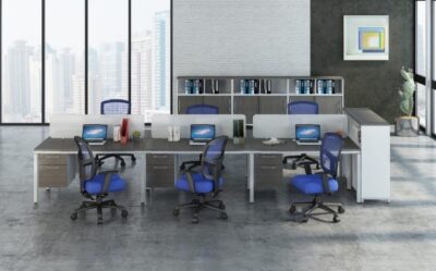 Blue office chairs sit at a pod of six workstations in a gray/concrete office space